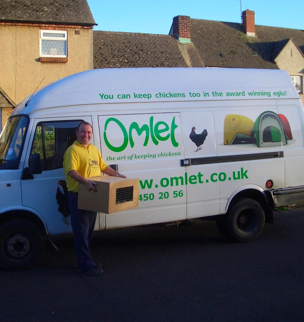 Kierowca dostawczy obok furGonetki marki Omlet przewożącej skrzynkę kurczaków